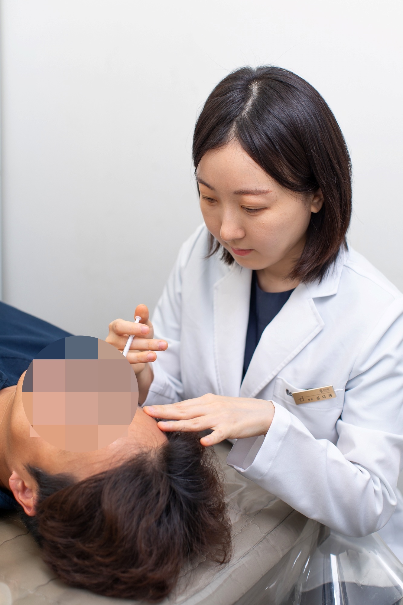 심다혜 원장이 누워 있는 환자의 얼굴 가까이에서 시술하는 모습