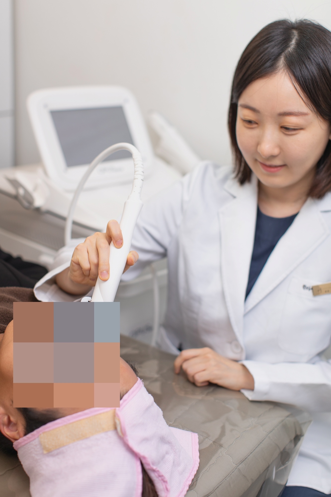 원장이 누운 환자의 얼굴 가까이에서 흰색 핸드피스를 들고 진행하는 시술 장면